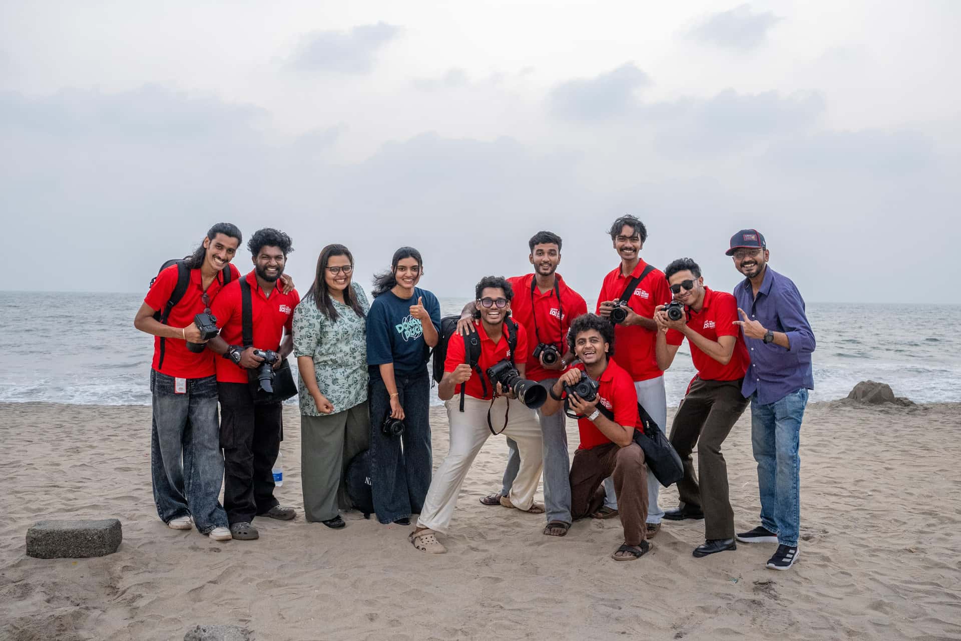 Large group of Legends Media Mastery students celebrating at the beach with cameras