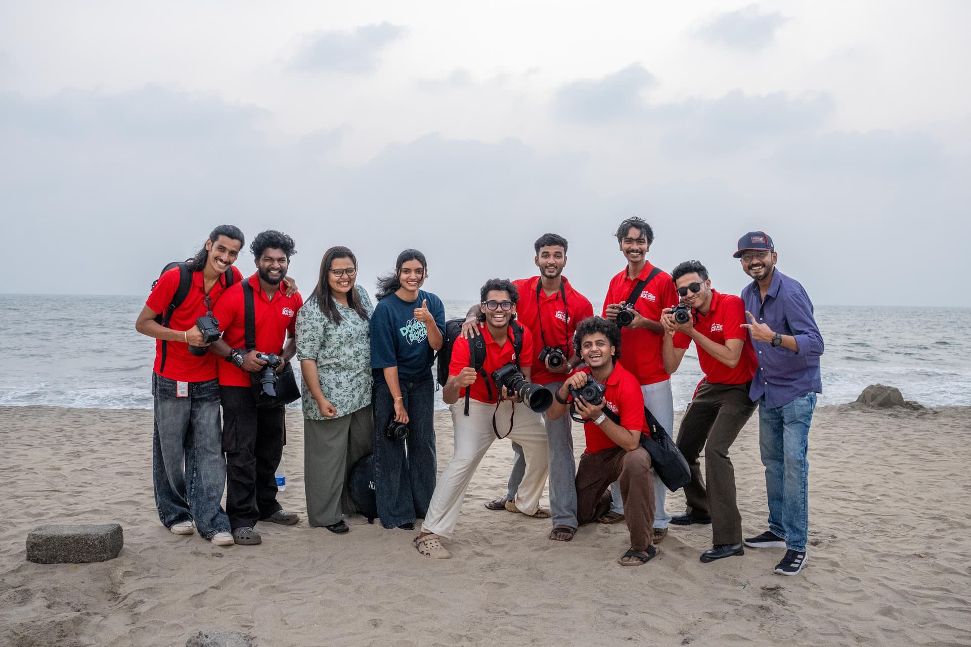 Large group of Legends Media Mastery students celebrating at the beach with cameras